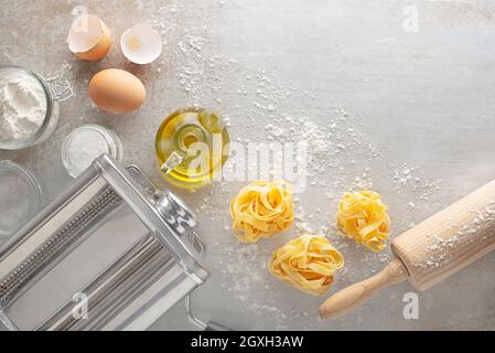 Making homemade fresh pasta with pasta machine on kitchen table with some ingredients around Stock Photo