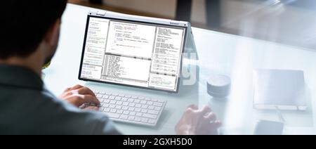 Programmer Or Coder At Office Desk Using Laptop Stock Photo
