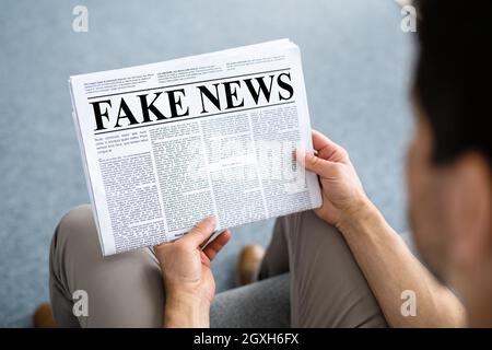 Businessman Reading Fake News Article On Newspaper In Living Room Stock Photo