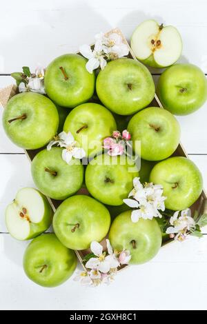 Apples fruits green apple fruit box on wooden board portrait format with leaves and blossoms food Stock Photo