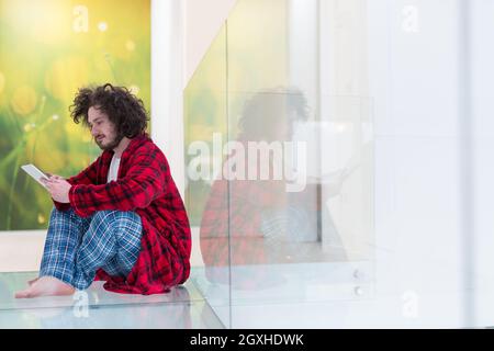 young freelancer in bathrobe working from home using tablet computer Stock Photo
