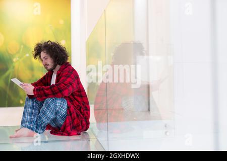 young freelancer in bathrobe working from home using tablet computer Stock Photo