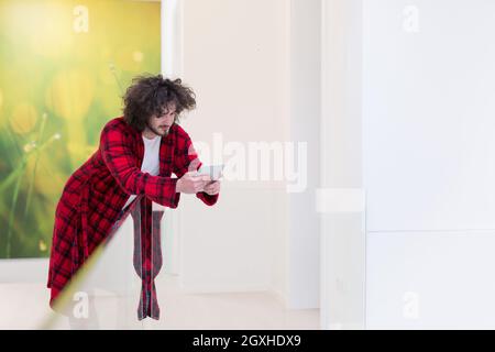 young freelancer in bathrobe working from home using tablet computer Stock Photo