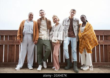 Full length portrait of diverse group of young people looking at camera while walking at seaside Stock Photo