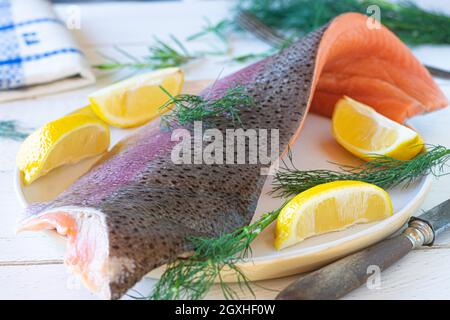 Raw and uncooked half salmon fillet on white background with lemon and dill. Fish with skin. Omega 3 source Stock Photo