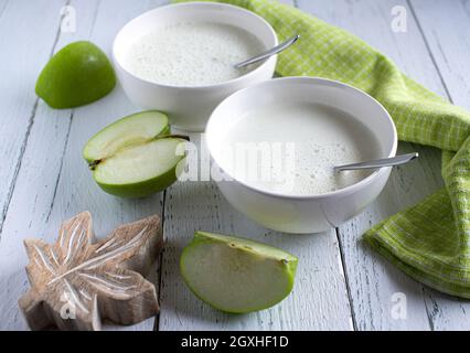 Homemade fresh blended organic yogurt with green apples served on a white wooden table isolated from above. Soft health concept Stock Photo