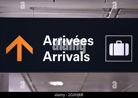 Bilingual arrivals sign board in english and french at airport terminal hall. Government open border for vaccinated international travellers visitors. Stock Photo