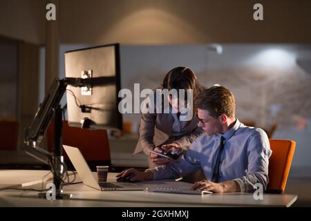 Two young designers are working on a new project in the night office using modern technology Stock Photo