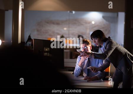 Two young designers are working on a new project in the night office using modern technology Stock Photo