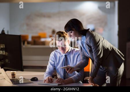 Two young designers are working on a new project in the night office using modern technology Stock Photo