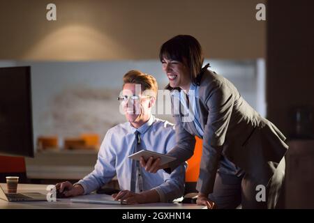 Two young designers are working on a new project in the night office using modern technology Stock Photo