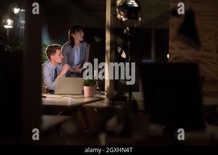 Two young designers are working on a new project in the night office using modern technology Stock Photo