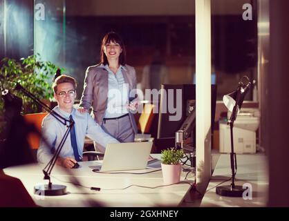 Two young designers are working on a new project in the night office using modern technology Stock Photo