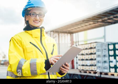 Supervisor checking contents of shipment to be sent by truck on her tablet computer Stock Photo