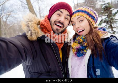 Photo of cheerful handsome man attractive lady take selfie have fun free time weekend in snowy forest outdoors Stock Photo