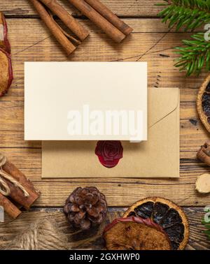 Winter Christmas Composition with a blank card and sealed envelope over wooden table flat lay. Christmas and New Year greeting card template with fir Stock Photo