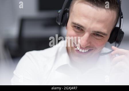 young smiling male call centre operator doing his job with a headset Stock Photo
