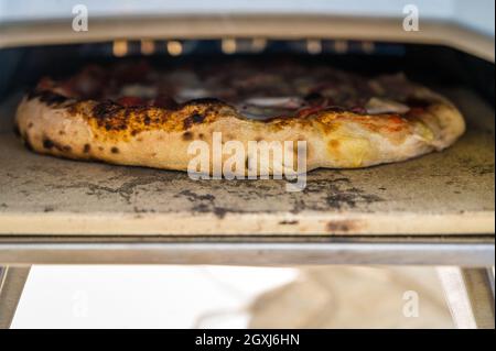 Making homemade pizza in portable high temperature gas pizza oven. Delicious pizza is baking in gas oven furnace for home made Neapolitan pizza. Speci Stock Photo