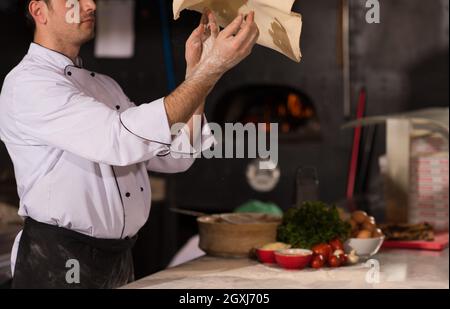 Skilled chef preparing dough for pizza rolling with hands and throwing up Stock Photo