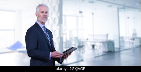 Portrait of senior businessman using tablet in front of his modern office Stock Photo