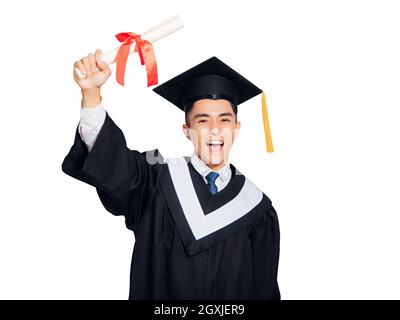 Excited young man in  black graduation gown and cap holding a diploma Stock Photo