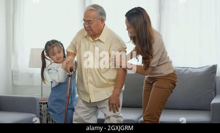 Asian family, Daughter and granddaughter take care support grandfather who is suffering from knee pain Got walking outside to take a walk And grandpa Stock Photo