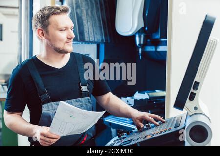 Young machine operator programming modern industrial cnc lathe Stock Photo