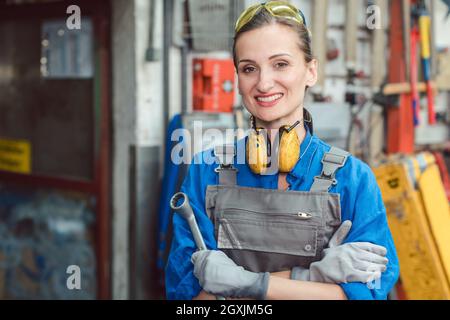 Woman worker in her metal workshop posing with tools for the camera Stock Photo