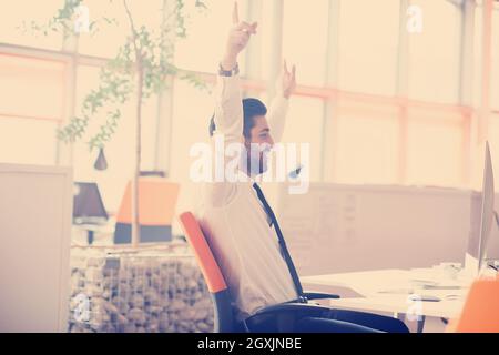 happy young business man  working on desktop computer at his desk in modern bright startup office interior Stock Photo