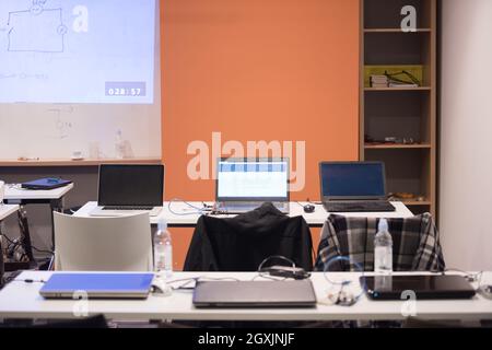 empty it classroom with program code on projector screen and modern laptop computers on table Stock Photo