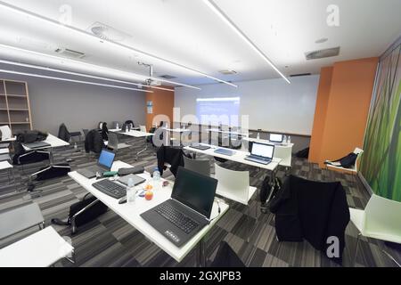 empty it classroom with program code on projector screen and modern laptop computers on table Stock Photo