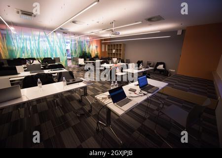 empty it classroom with program code on projector screen and modern laptop computers on table Stock Photo