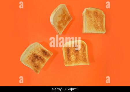 Flying roasted pieces of bread on orange pastel background. Fresh roasted pieces of toasts on orange background. Minimal style concept. Space for text Stock Photo