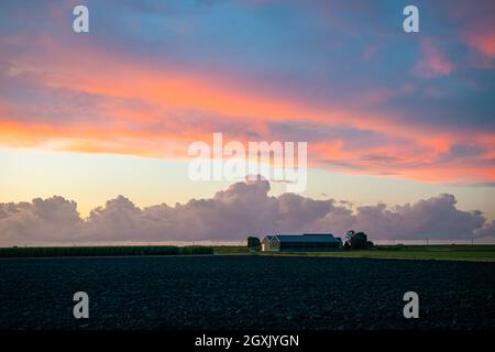 Farm in wide open Dutch countryside under a colorful sky Stock Photo