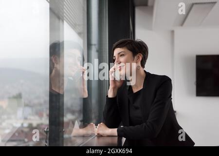 female manager using cell telephone in office interior Stock Photo