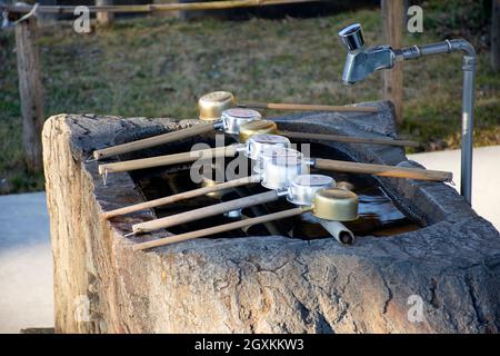 Ladles or hishaku arranged over a stone basin or temizuya at the entrance of Kanjizai-ji Buddhist temple, Ainan, Ehime Prefecture, Japan Stock Photo