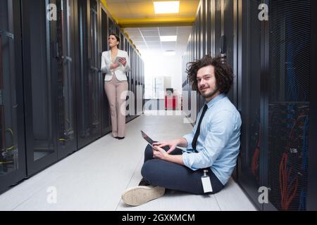 Team of young technicians working together on servers at the data center using tablet computers Stock Photo