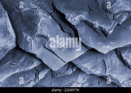 Embossed and rough dark stone or rock texture of mountains divided by huge cracks and layers. Banner with copy space for your design. Decorative rock Stock Photo