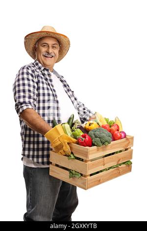 Smiling mature farmer holding broccoli and standing behind a crate with ...