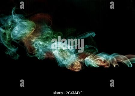 Green and orange smoke twisting on a black background Stock Photo