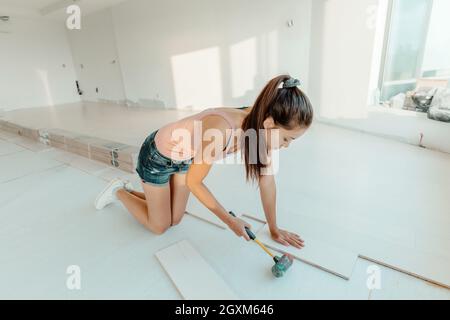 Engineered hardwood new floor installation in house remodeling woman installing wood flooring herself DIY project Stock Photo