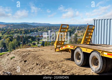 A tractor trailer parks on the edge of a hillside dirt lot ready for a new home overlooking the cities of Greenacres, Liberty Like, Spokane Washington Stock Photo