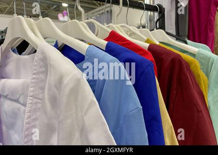 Assortment of variety of casual clothes hanging on rack at shop boutique for sale. Close-up. Indoors. Stock Photo