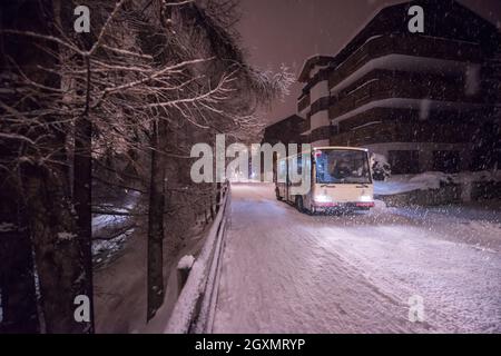 Electric taxi bus on snowy streets in the car-free Alpine mountain village at cold winter night Stock Photo