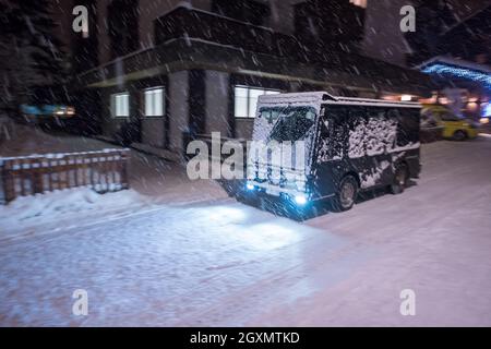 Electric taxi bus on snowy streets in the car-free Alpine mountain village at cold winter night Stock Photo