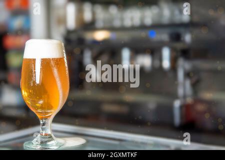 Glass of beer on the bar counter, fresh, beautifully colored with the foam falling through the glass Stock Photo