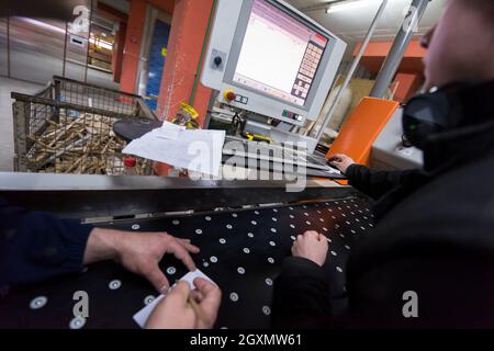 two young carpenters calculating and programming a cnc wood working machine in workshop. wood workers preparing a computer program for CNC machine at Stock Photo