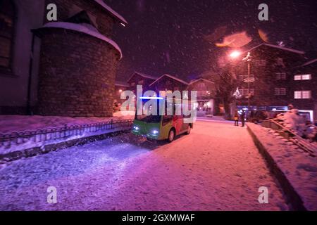 Electric taxi bus on snowy streets in the car-free Alpine mountain village at cold winter night Stock Photo