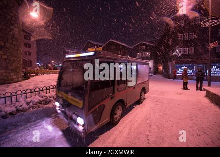 Electric taxi bus on snowy streets in the car-free Alpine mountain village at cold winter night Stock Photo