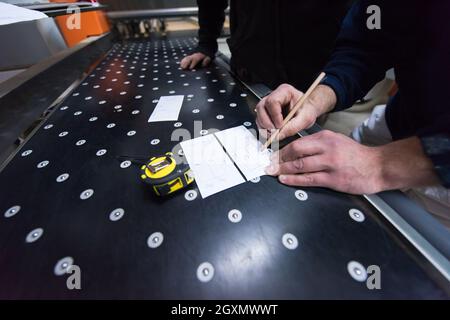 two young carpenters calculating and programming a cnc wood working machine in workshop. wood workers preparing a computer program for CNC machine at Stock Photo